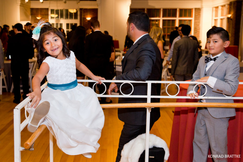 A little girl is standing on a railing during a wedding.