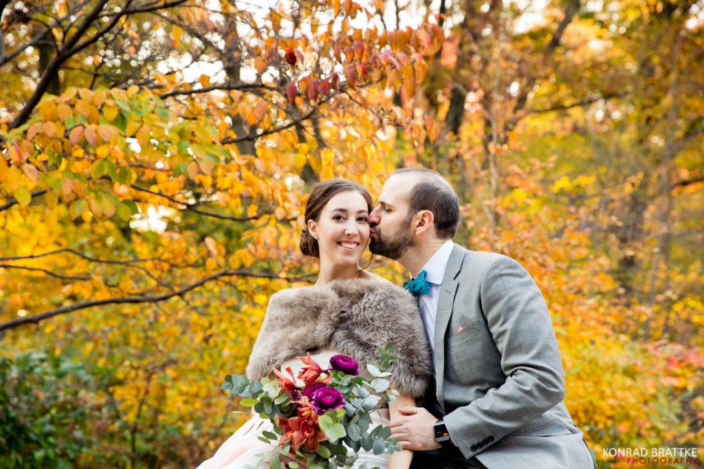 A bride and groom kissing in Prospect Park during their autumn leaves wedding.