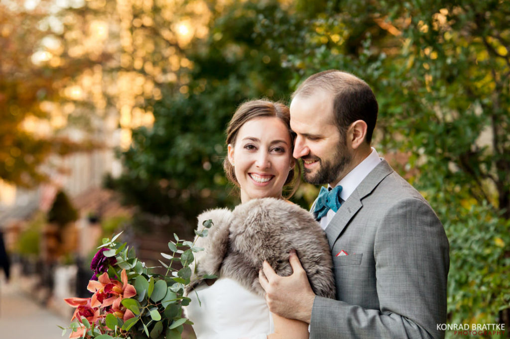 A bride and groom are posing for a photo in front of a building at their wedding.
