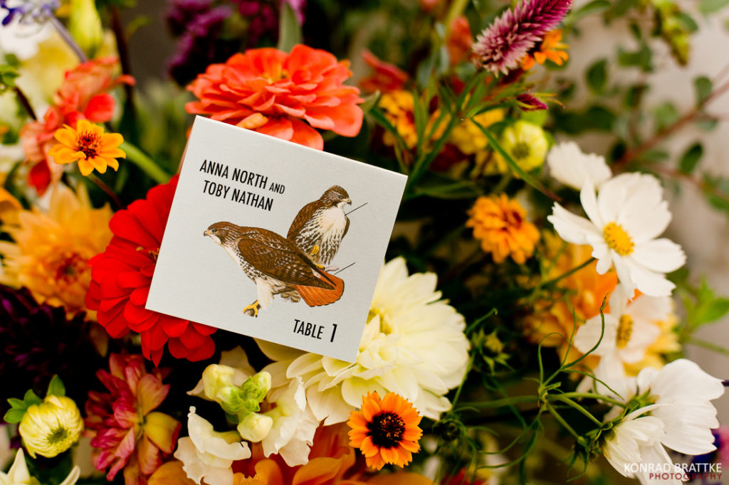 A card with a picture of a hawk perched amidst a bouquet of flowers.
