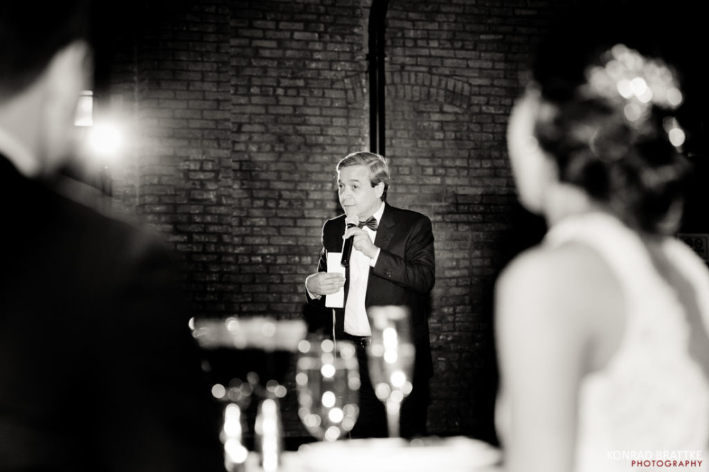A man is giving a speech at 26 Bridge, a wedding venue.