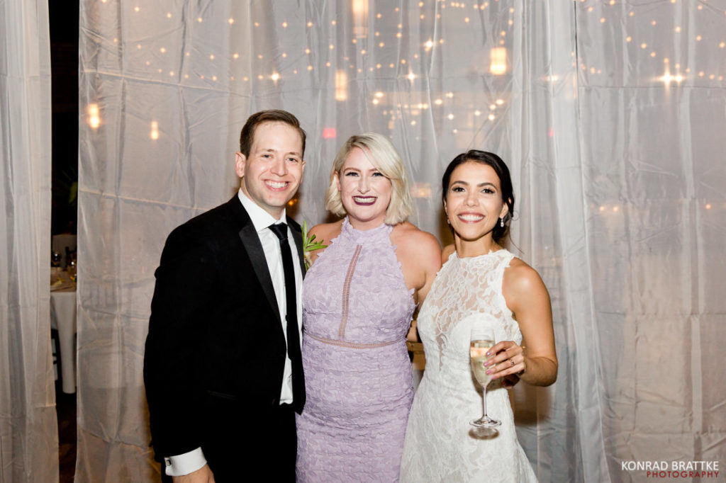 Three people posing for a photo at the 26 Bridge wedding reception.