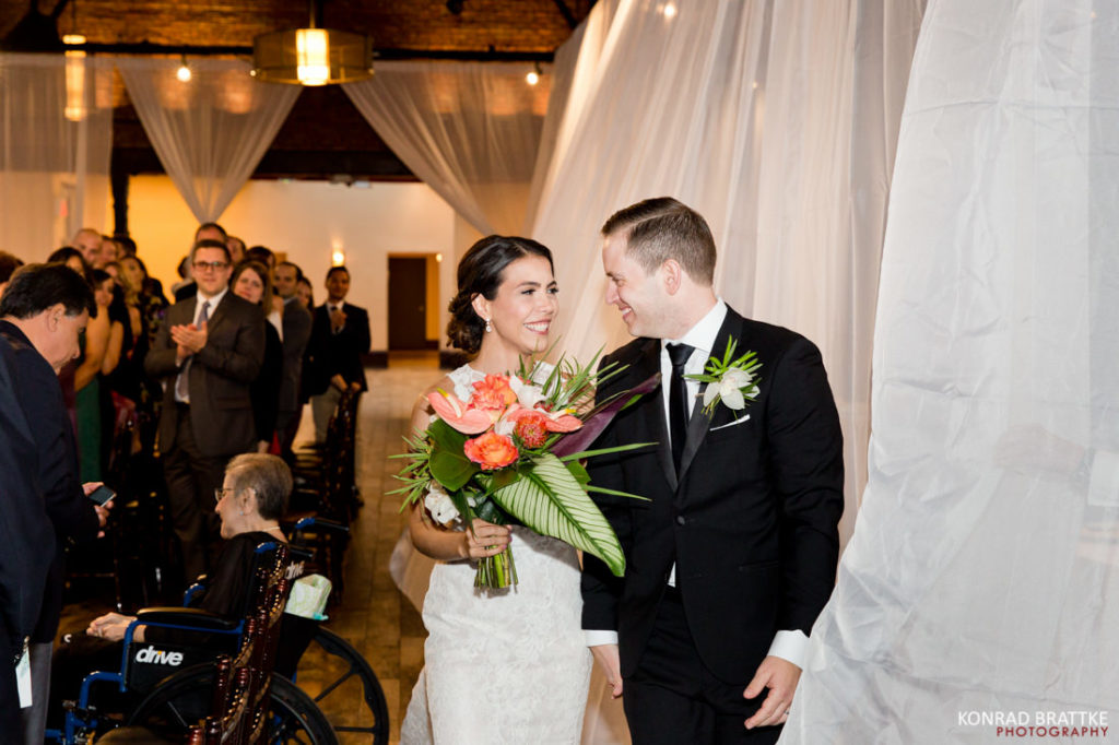 A bride and groom walking down the aisle at 26 Bridge.