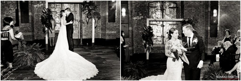 A bride and groom share a passionate kiss in front of the 26 Bridge, a stunning brick wall backdrop.