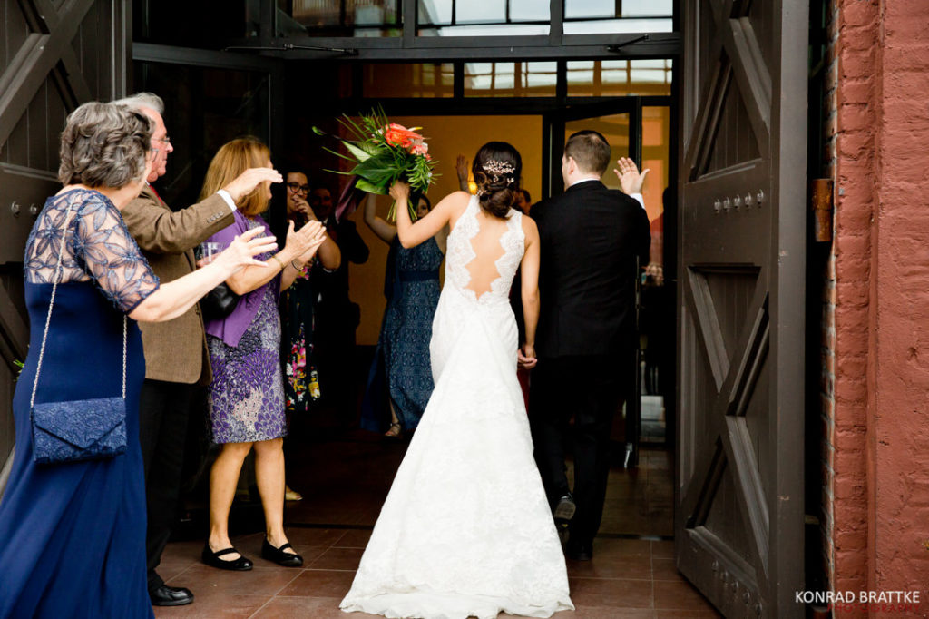 A couple, the bride and groom, joyfully entering from the iconic 26 Bridge venue.