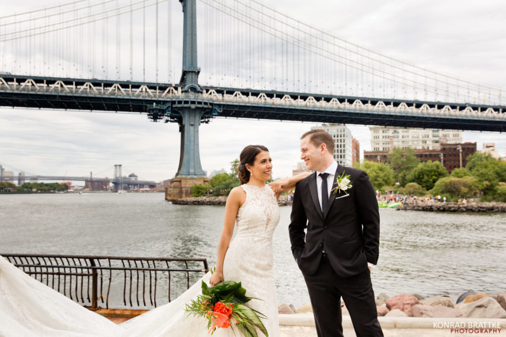 A bride and groom standing in front of the Manhattan Bridge.