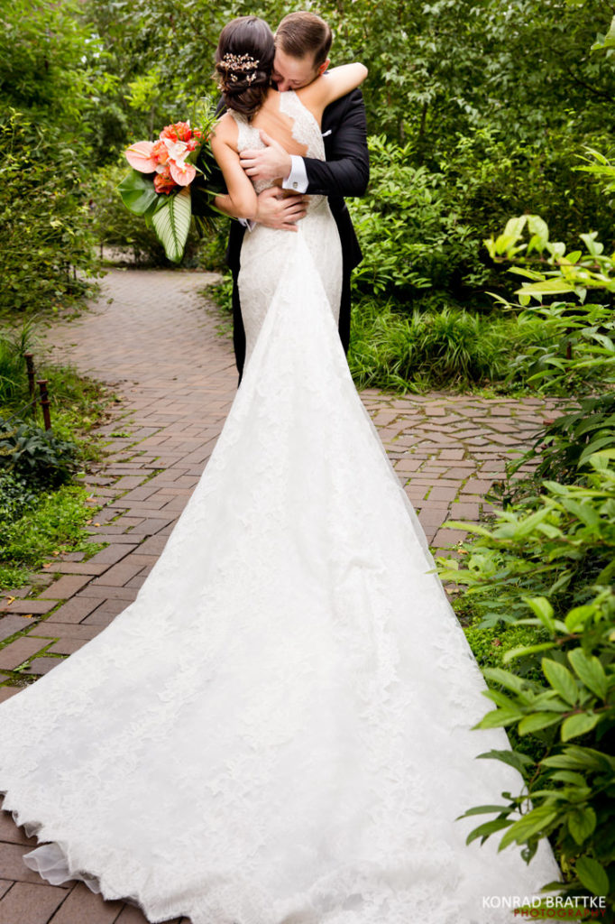 A bride and groom hugging surrounded by lush woods.