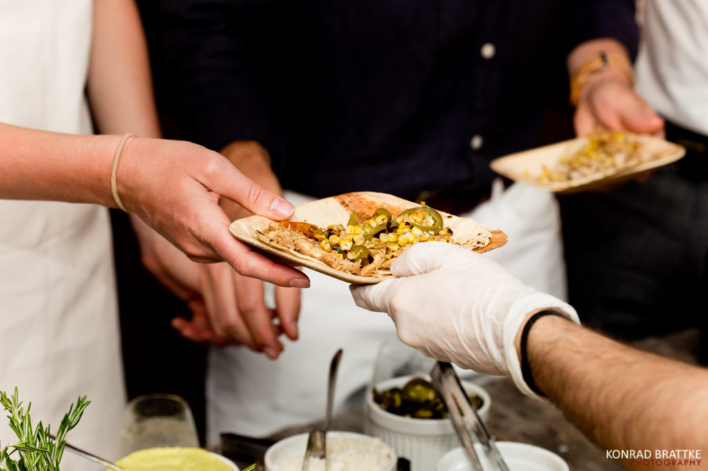 At a Brooklyn Grange wedding, one person graciously passes a plate of delectable food to another person.