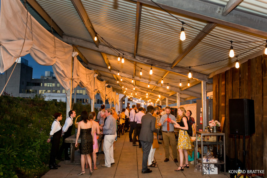 A group of people under a tent at an outdoor Brooklyn Grange wedding.