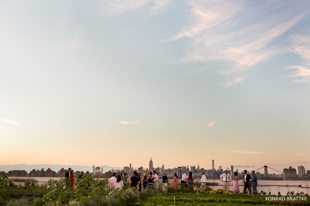 A group of people enjoying a Brooklyn Grange Wedding at sunset in a field.