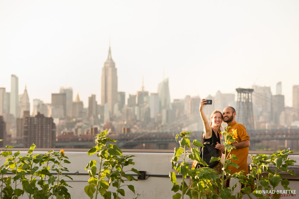 A couple capturing a breathtaking picture on the Brooklyn Grange rooftop overlooking stunning New York City. The perfect spot for an unforgettable wedding moment.