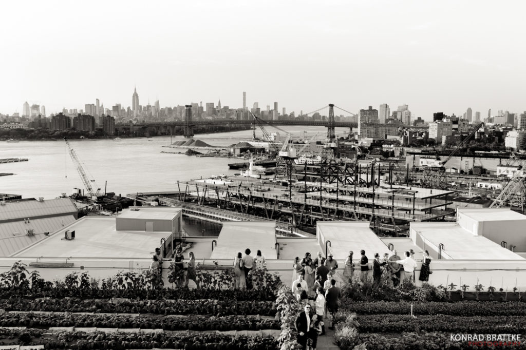 A black and white photo of people on a rooftop with a view of the city, capturing the essence of a Brooklyn Grange Wedding.