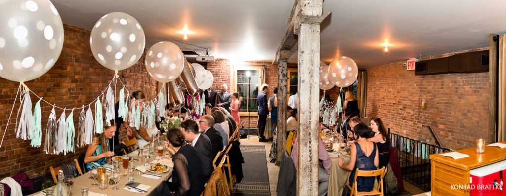 A group of people sitting at a table during a brooklyn wedding celebration, surrounded by balloons.