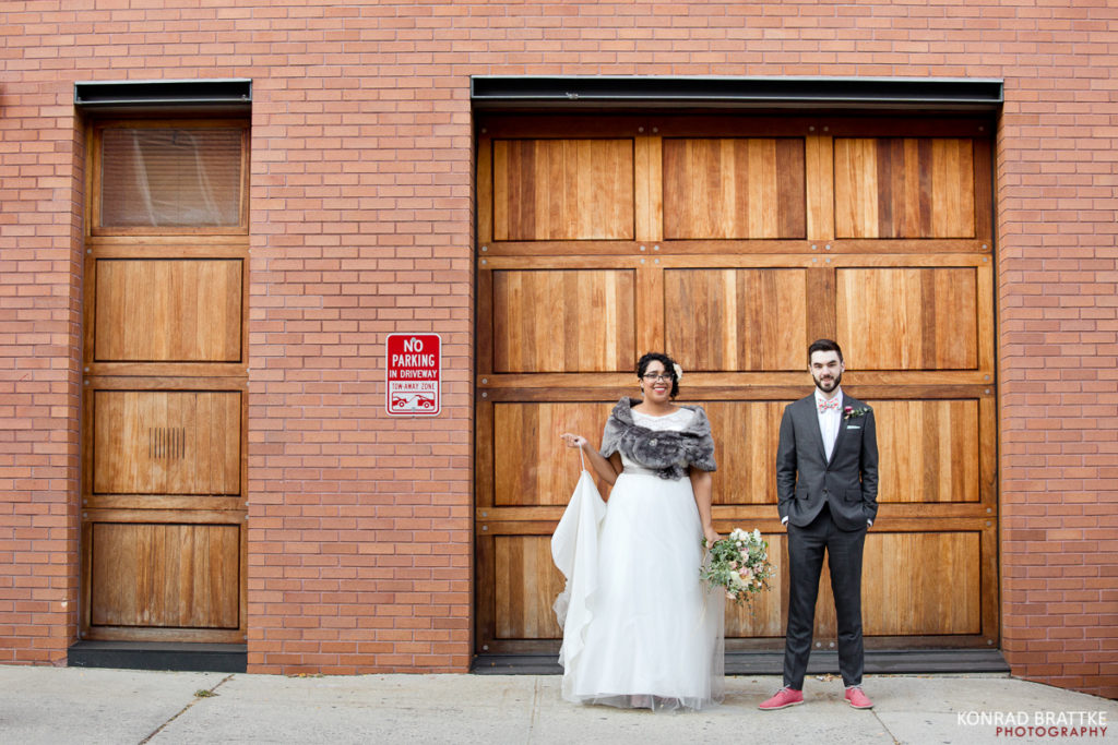 A Brooklyn bride and groom standing in front of a brick building.