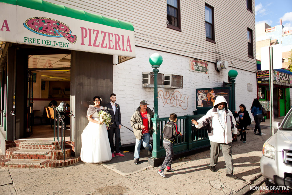 A Brooklyn wedding couple walking outside of a pizza restaurant.