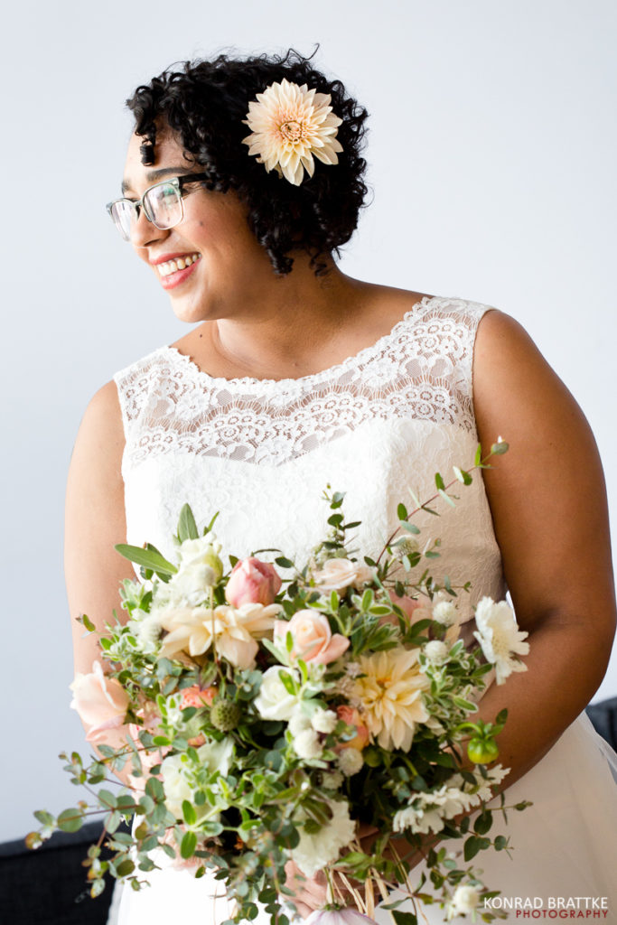 A Brooklyn bride with glasses holding a bouquet of flowers.