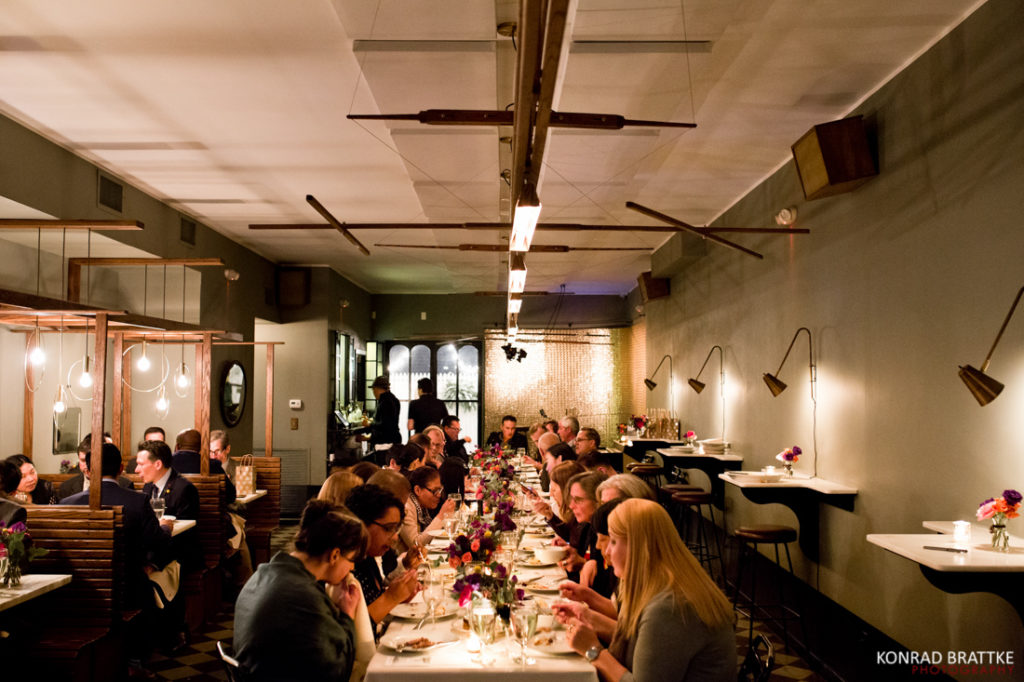 A group of people sitting at a table in the Le Fanfare restaurant during a wedding reception.