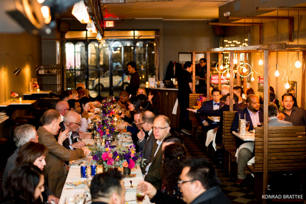 A group of people sitting at a long table in Le Fanfare, a restaurant.