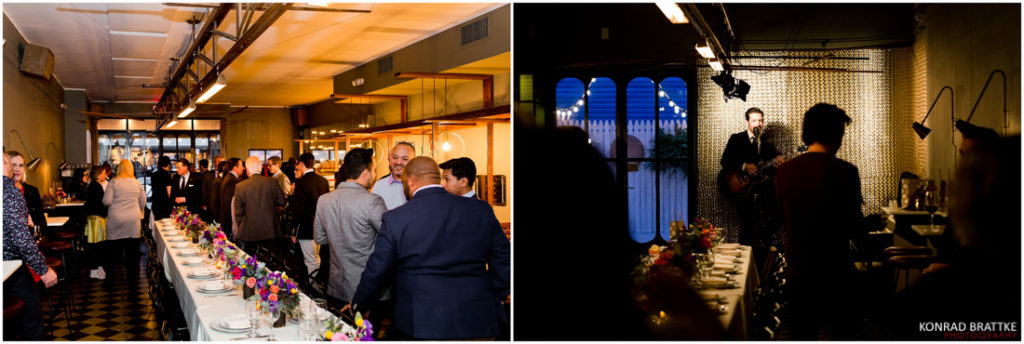 A group of people standing at a table in a dark room enjoying their meal at Le Fanfare.