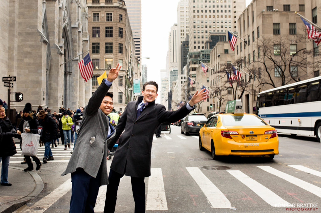 Two grooms standing on a street in New York City.