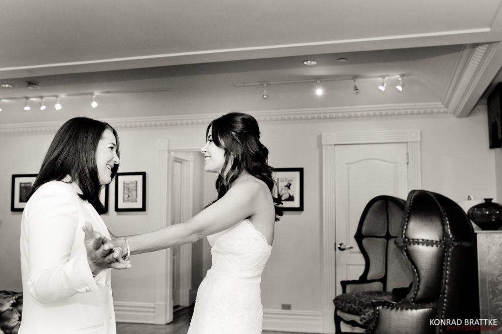 Two brides embracing in a black and white photo taken at their elegant Manhattan Penthouse wedding.