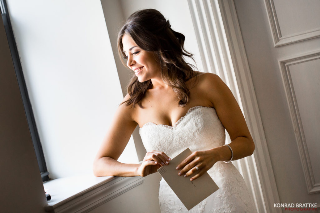 A bride in a wedding dress leaning against a window at a Manhattan Penthouse wedding.