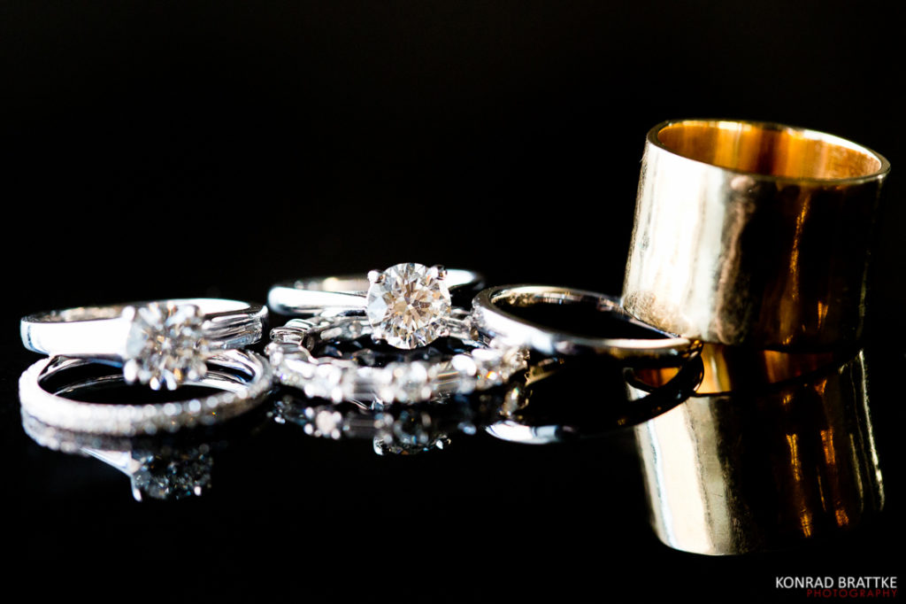 A stunning collection of wedding rings, including a mesmerizing gold ring, gracefully placed on a sleek black surface.