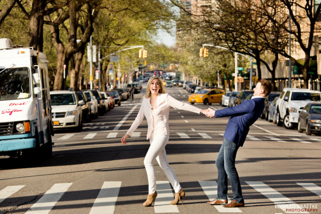 A man and woman are crossing a street in NYC, capturing the vibrant essence of city life at its best.