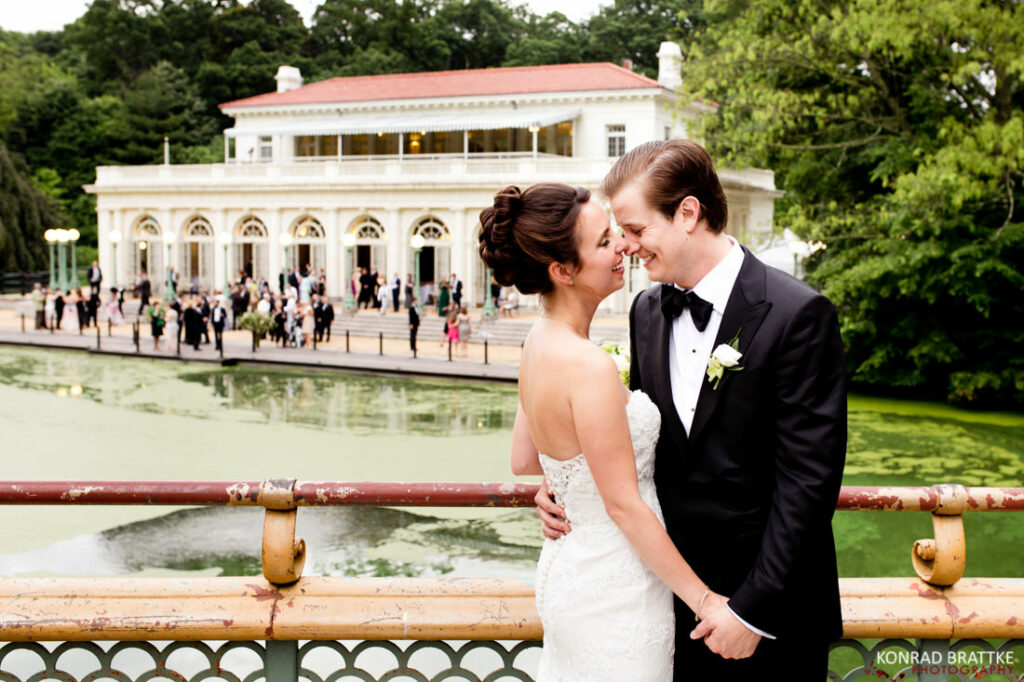 The bride and groom share a romantic kiss in front of a beautiful pond.