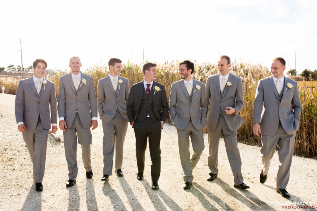 The best of weddings - a group of groomsmen in gray suits walking down a path.