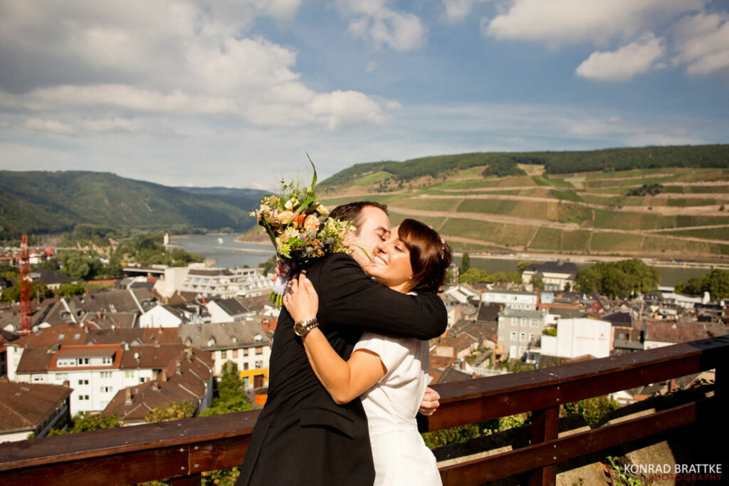 The best of weddings captured in a romantic moment, with a bride and groom kissing on a balcony overlooking the Rhine River.