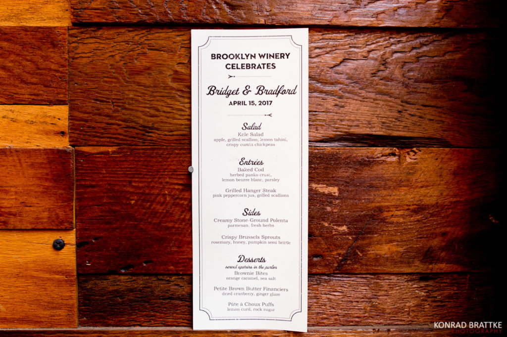 A Brooklyn Winery wedding menu hanging on a wooden wall.