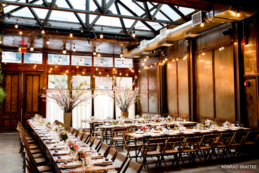 A wedding reception set up at Brooklyn Winery with wooden tables and chairs.