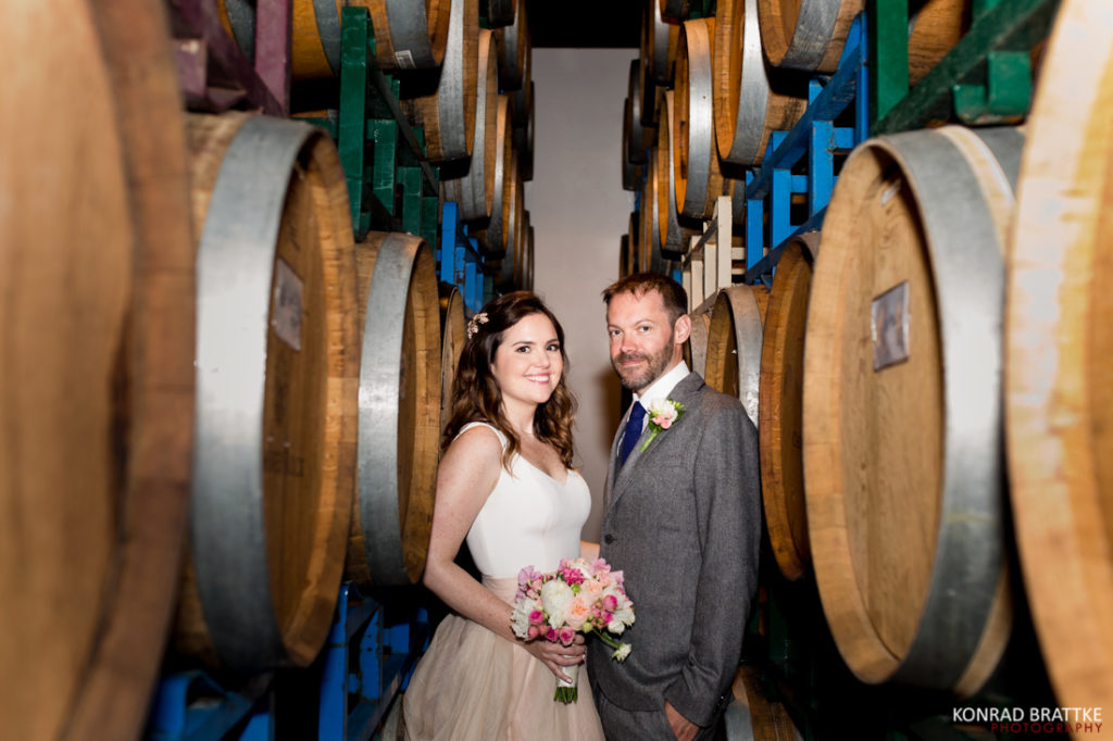 A bride and groom posing elegantly at Brooklyn Winery, with wine barrels adding a touch of rustic charm to their backdrop.