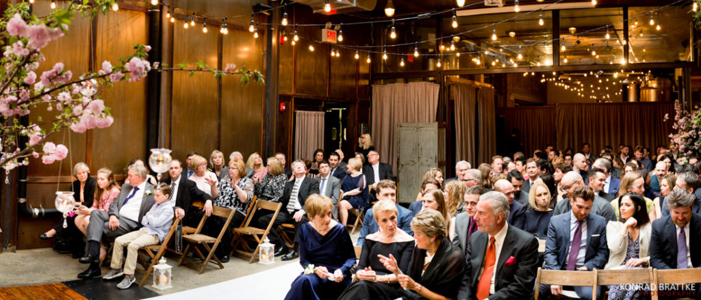A wedding ceremony at Brooklyn Winery, filled with a large gathering of people.
