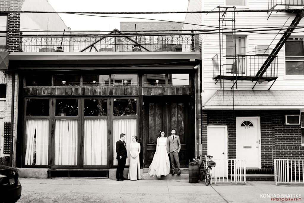 A black and white photo of a bride and groom in front of Brooklyn Winery.