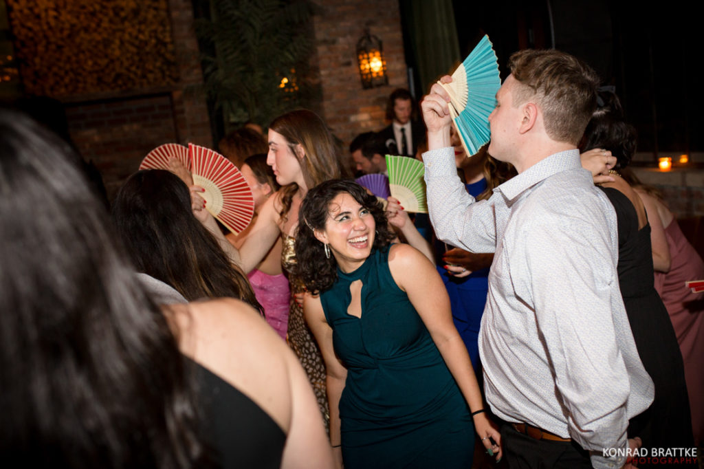 A group of people at a party with fans in their hands, celebrating at a Bowery Hotel wedding.