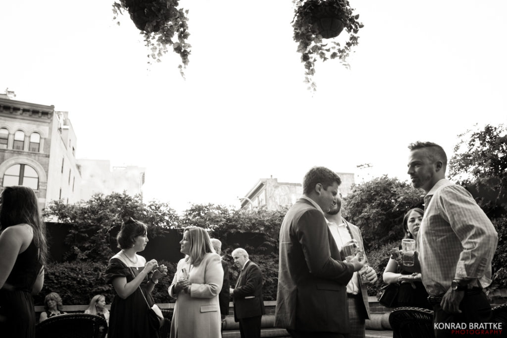 A black and white photo of a group of people in a courtyard at a Bowery Hotel wedding.