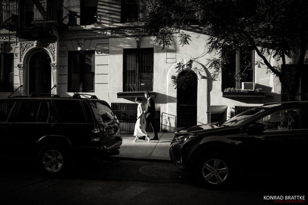 A black and white photo of a couple walking down the street near the Bowery Hotel.