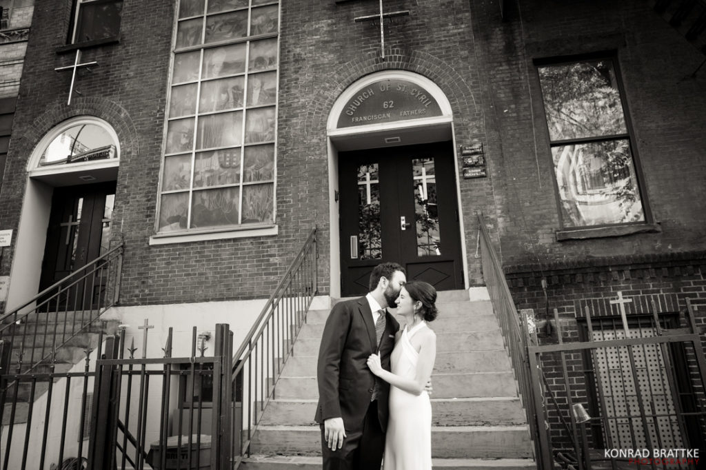 A bride and groom share a romantic kiss, capturing the essence of their beautiful wedding day against the backdrop of an elegant brick building.