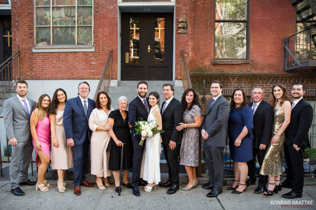 A wedding party posing in front of a church.