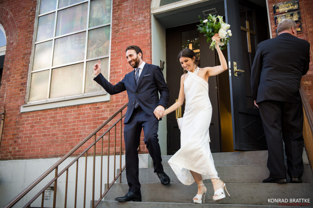 A wedding couple gracefully walking down the steps of a building.