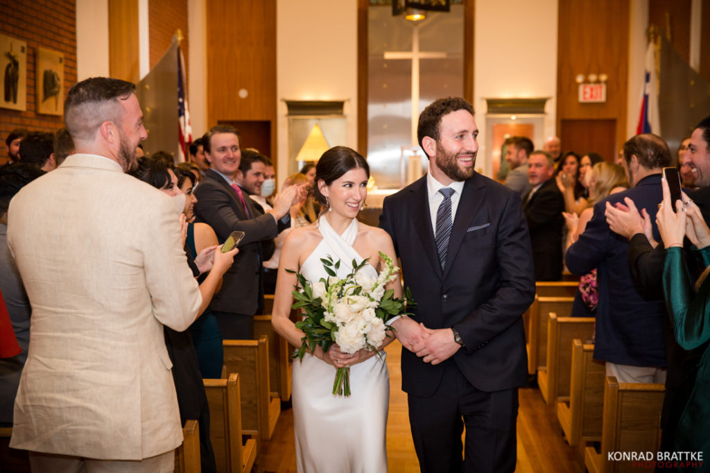 A bride and groom walk down the aisle of a church, celebrating their memorable wedding.