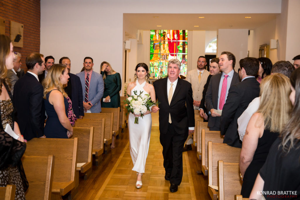 A bride walking down the aisle at her wedding with her father.