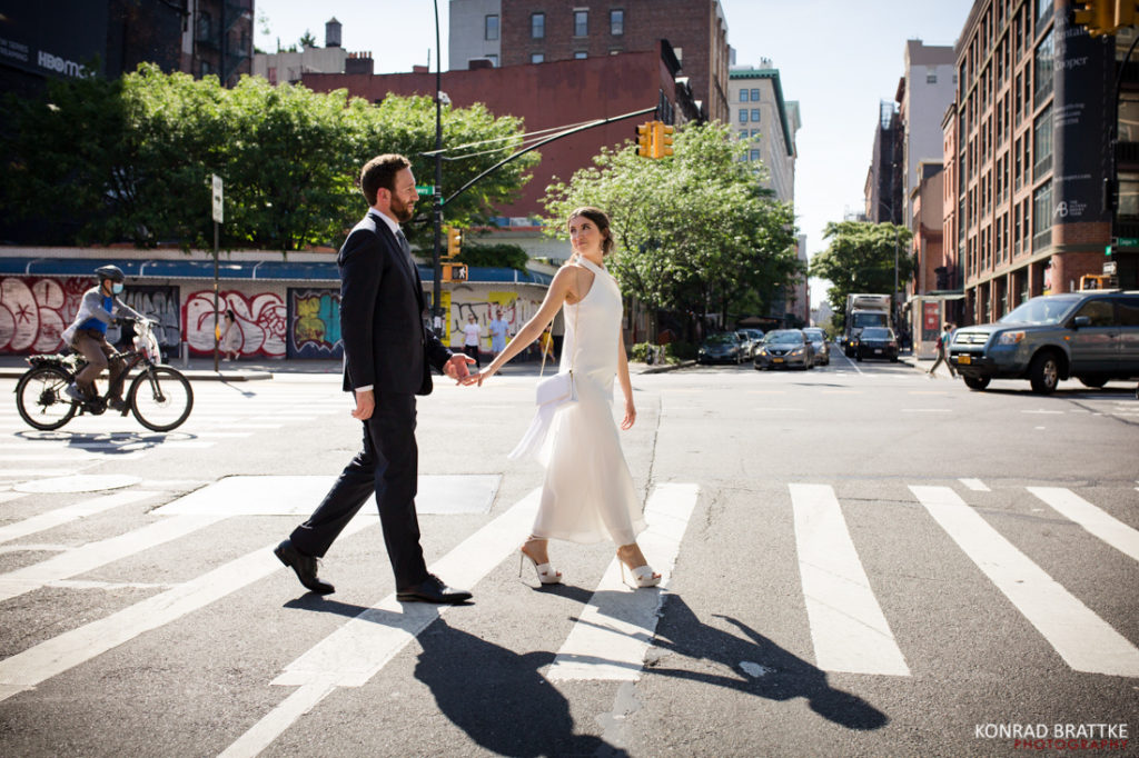 A bride and groom cross the street in front of the Bowery Hotel on their wedding day.