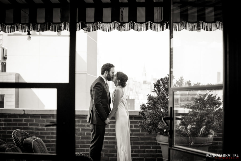 A bride and groom sharing a romantic kiss on the balcony of the Bowery Hotel.