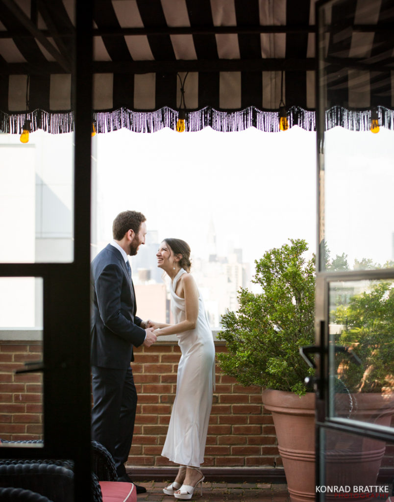 A bride and groom standing on the balcony of the Bowery Hotel.
