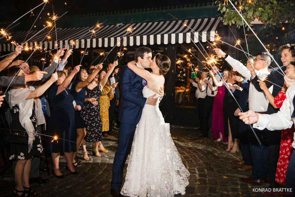 A bride and groom kissing in front of sparklers at the river cafe in Brooklyn, New York.