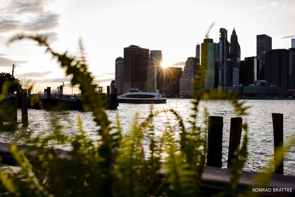The sun is setting over a body of water with a city skyline in the background seen from the river cafe.