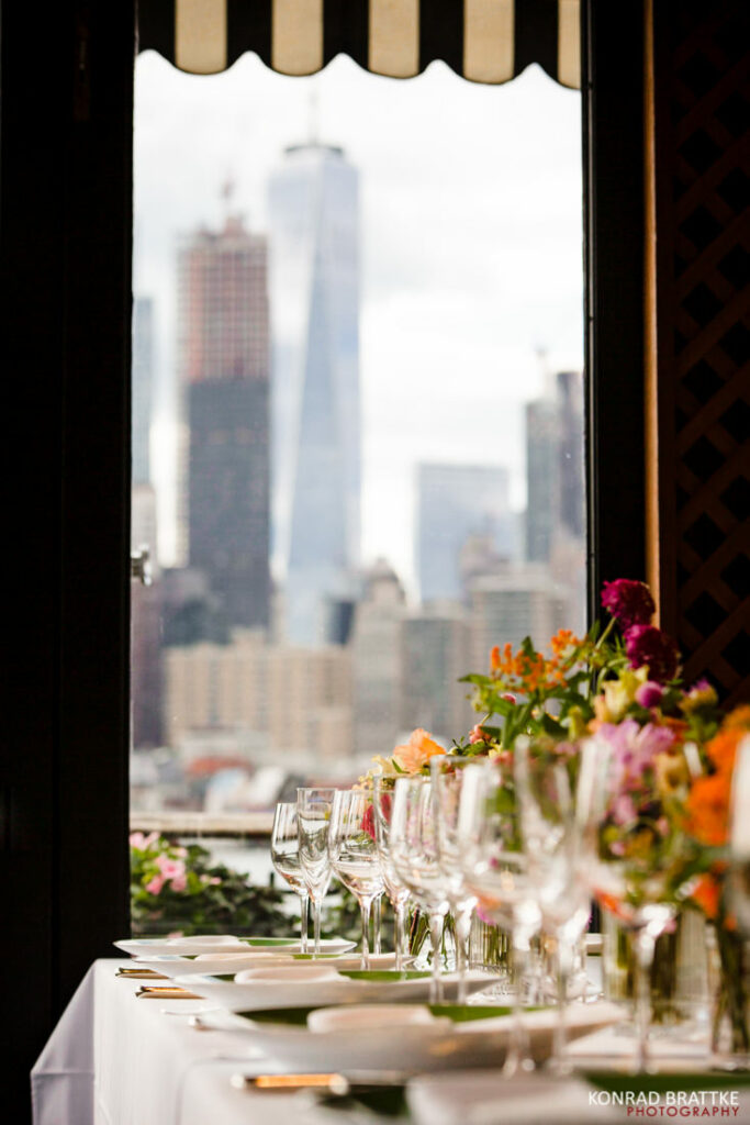 A table set with flowers and a view of the city at the river cafe.